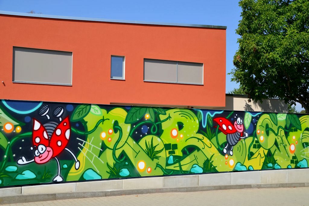 Außenansicht mit bunter Graffitimauer auf der Marienkäfer zu sehen sind