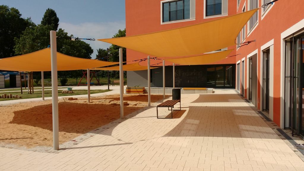 Blick auf den großen Sandspielplatz mit orange farbenen Sonnensegeln