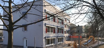 Außenansicht des sanierten Kita-Gebäudes mit Blick auf den Spielplatz