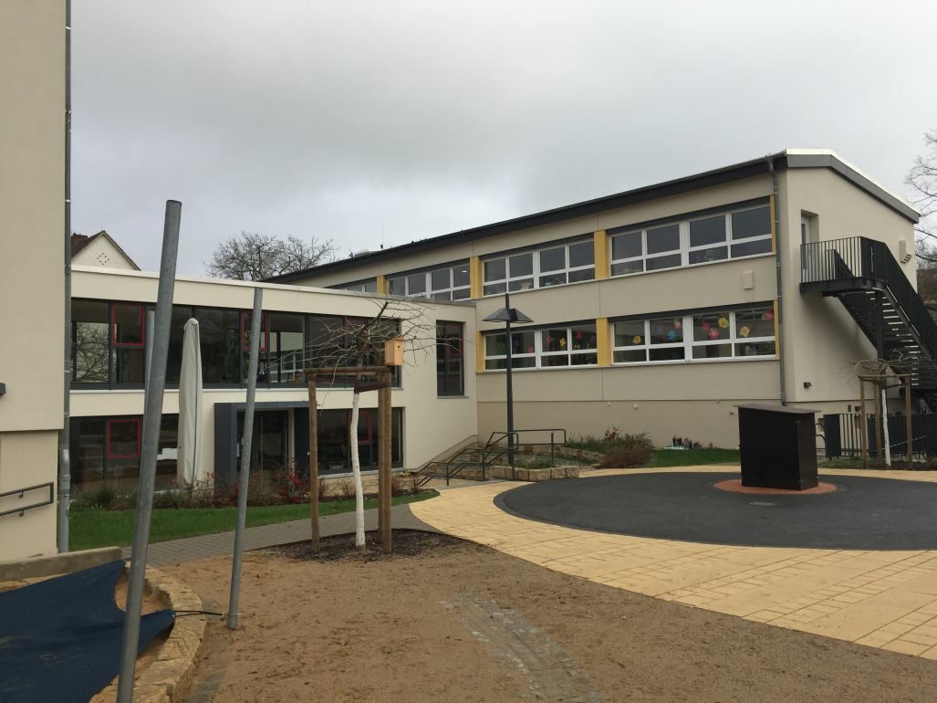 Ansicht auf die Rückseite mit Teilen des Spielhofes und einem Baum
