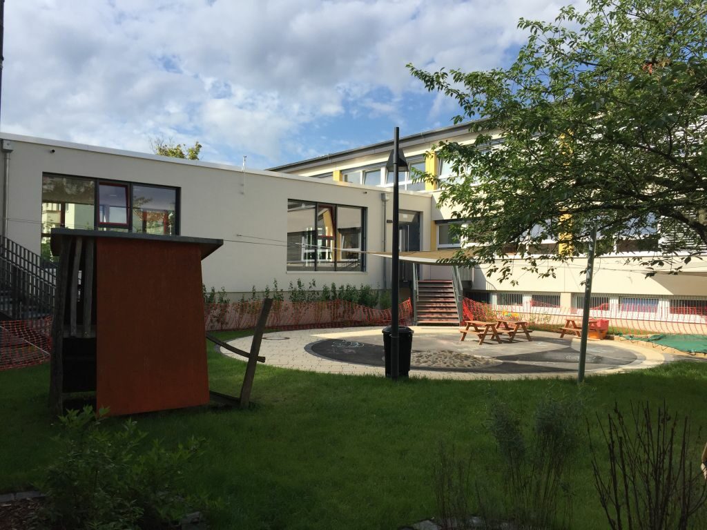 Ansicht des Innenhofes mit Bänken und Sonnensegel