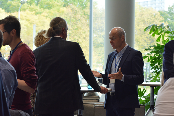 Prof. Breidung und Dr. Anke stehen am Hochtisch im Foyer und unterhalten sich