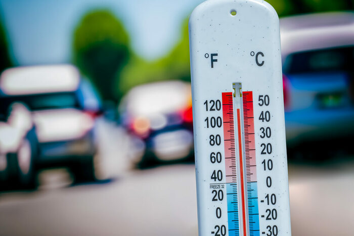 Thermometer mit hoher Gradzahl und im Hintergrund Autos auf einer Straße