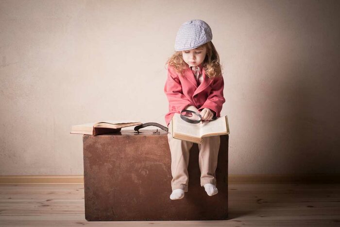Ein kleines Mädchen sitzt wartend auf einem Koffer.