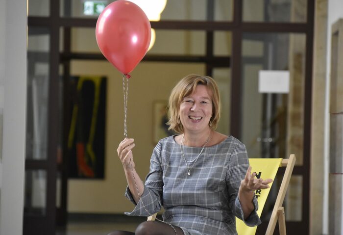 Anke Lietzmann, Kinder- und Jugendbeauftragte, sitzt auf einem gelben Liegestuhl und hält einen roten Luftballon in der Hand
