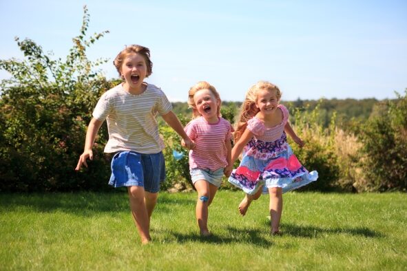drei Kinder laufen auf einer Wiese