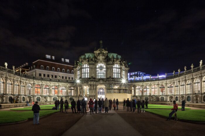 Bürgerinnen und Bürger versammeln sich vor dem Glockenspiel aus Meissener Porzellan im Dresdner Zwinger.