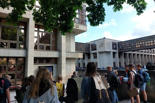 Eine Gruppe Schülerinnen und Schüler steht vor dem modernen Erweiterungsgebäude der Semperoper Dresden.