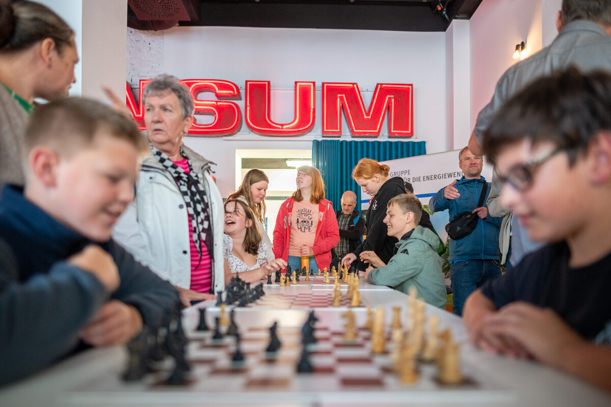 Kinder am einem langen Tisch mit mehreren Schachspielen