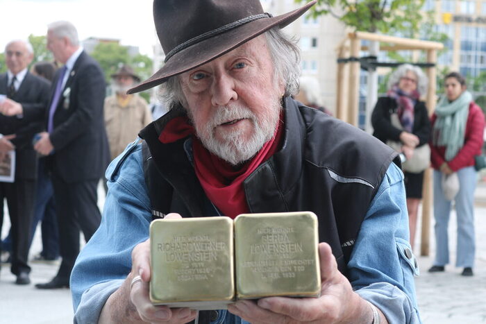 Künstler Gunter Demnig hält zwei Stolpersteine in den Händen.