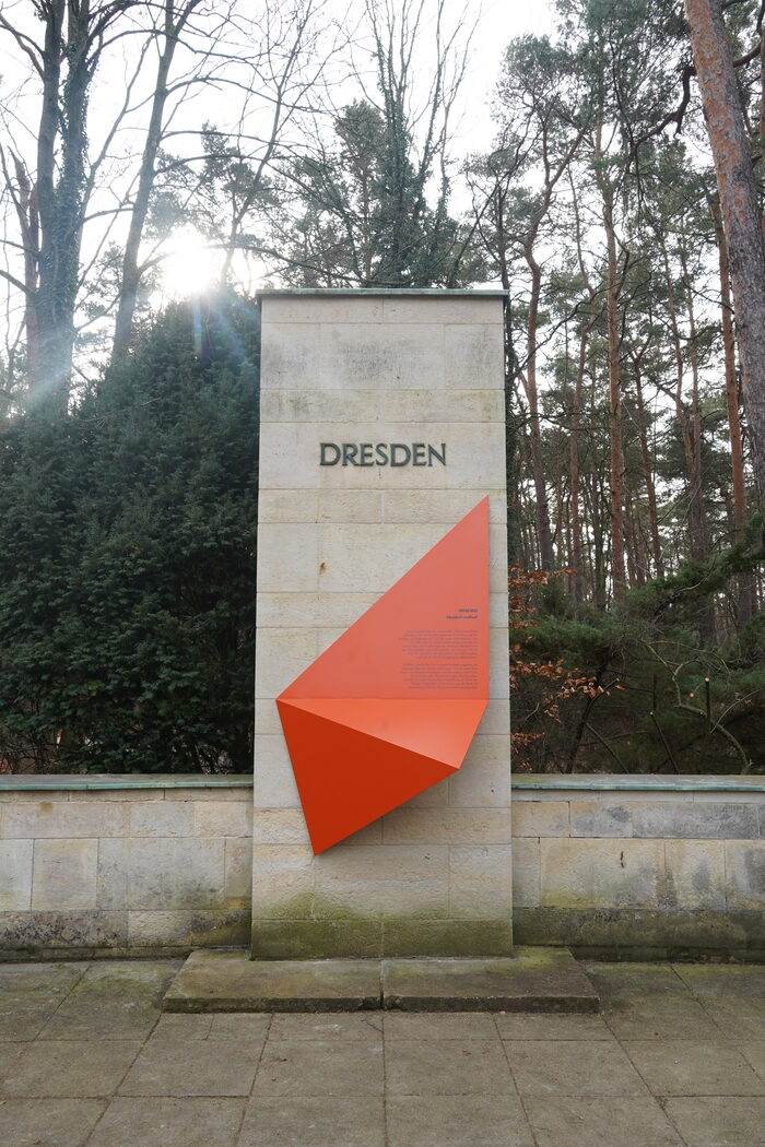 Gedenkstele aus Stein mit der Aufschrift Dresden, im Hintergrund sind Bäume