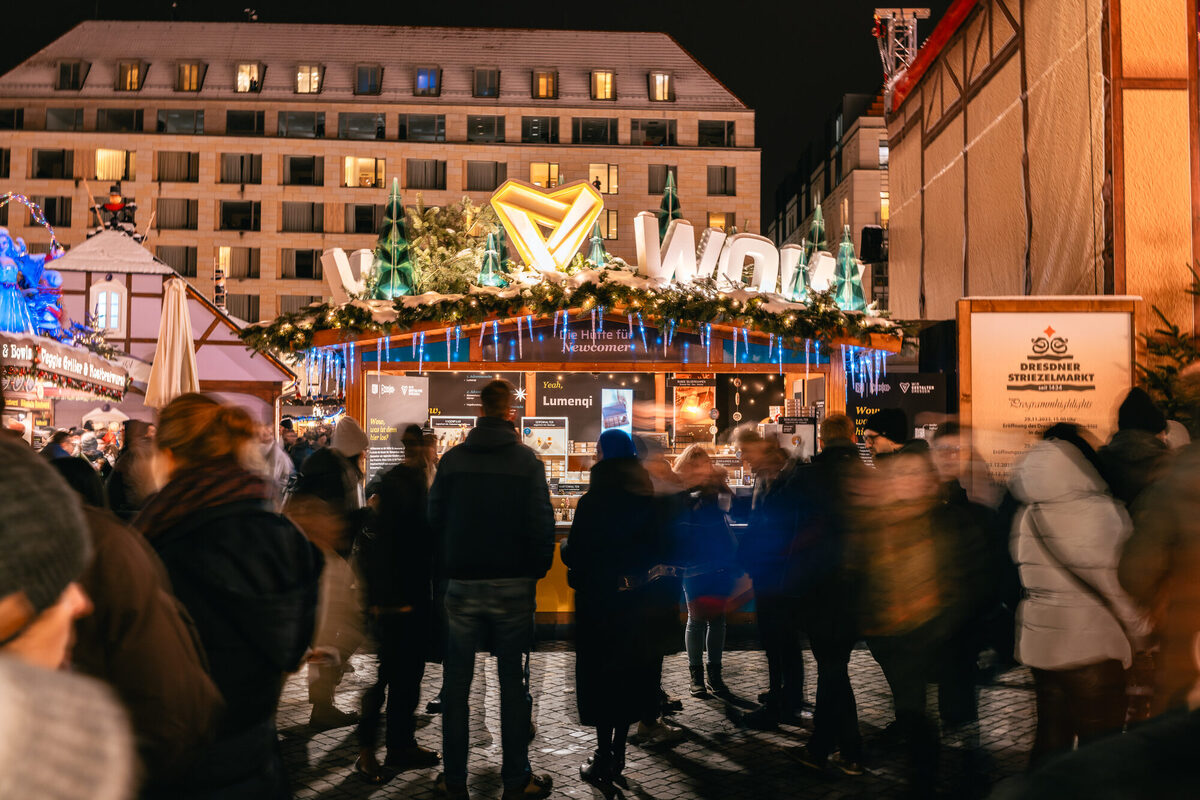 Voller, winterlicher Markt mit einem Verkaufsstand, an dem blau leuchtende Eiszapfen hängen