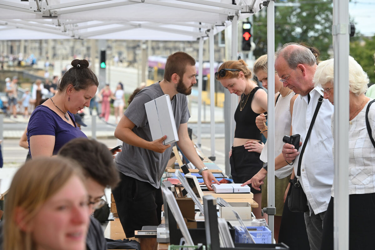 Menschen an einem Stand und Personen, die Flyer anschauen