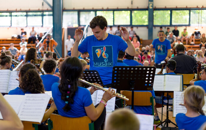 Ein junger Mann dirigiert ein Orchester.