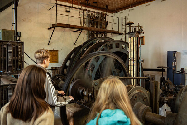 Drei Personen stehen vor einer alten Maschine.