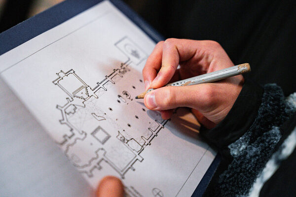 Eine Person zeichnet auf einem Grundriss einer Kirche etwas ein.