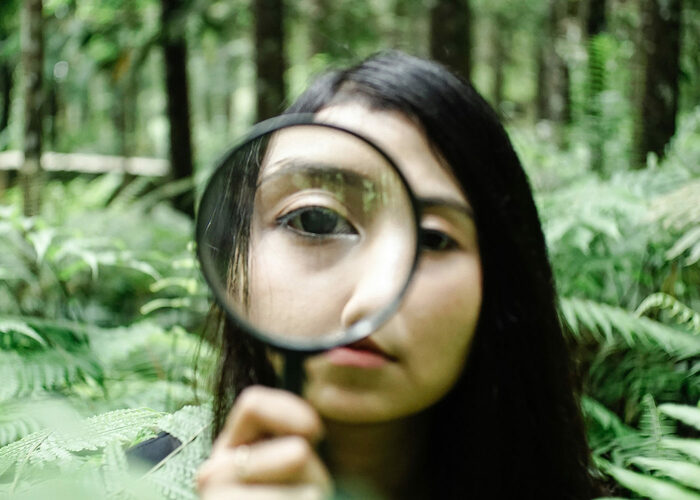 Girl looks through a magnifying glass and explores the vegetation