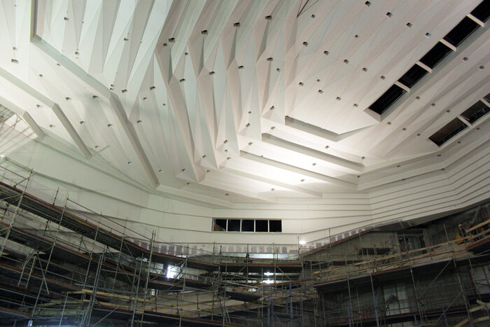 weiße strukturierte Saaldecke, darunter ein Baugerüst