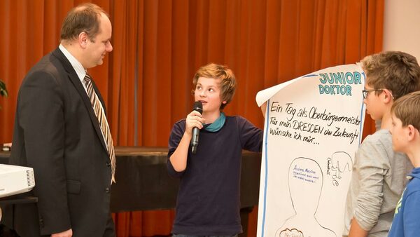Ein Schüler zeigt dem Oberbürgermeister sein Plakat und erläutert die gezeichneten Ideen