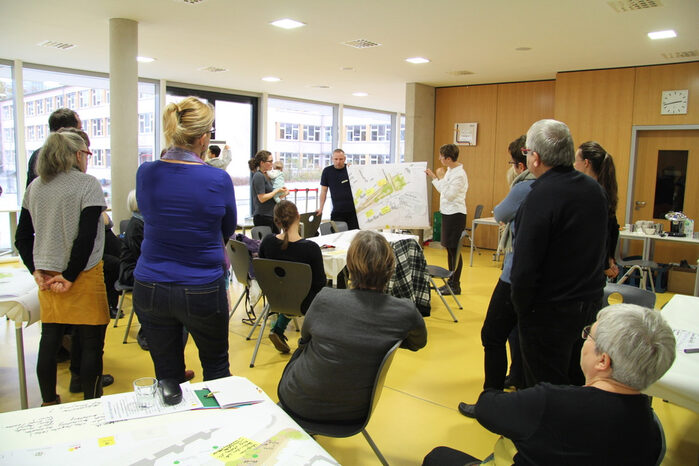 Menschen betrachten die Präsentation eines Lageplans