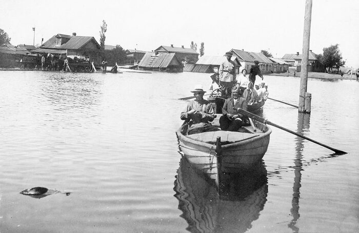 Boot mit Menschenauf dem Wasser, dahinter Häuser die bis zum Dach im Wasser stehen