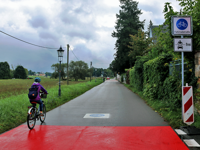 Kleinzschachwitz: Erste Fahrradstraße in Dresden. Straße mit roter Markierung. Ein Radfahrer ist unterwegs.