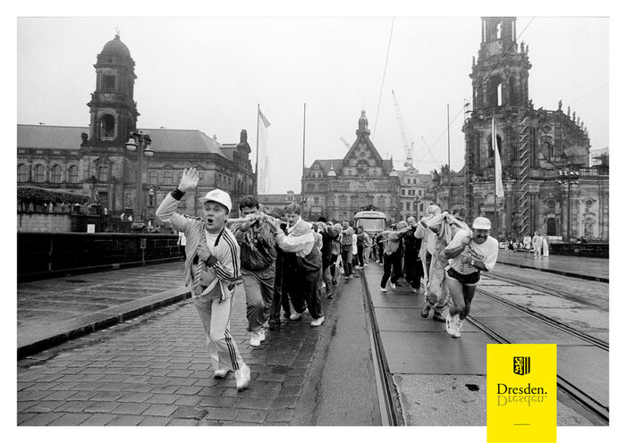 Schwarz-weiß Foto von Männern, die eine Straßenbahn an Seilen über die Augustusbrücke in Dresden ziehen