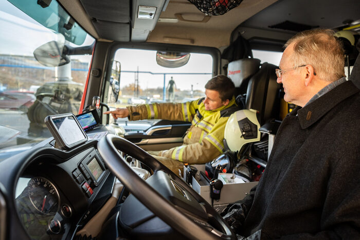 Foto vom Ersten Bürgermeister Detlef Sittel, der sich in der Fahrerkabine eines Feuerwehr-Autos von Maschinist David Giller das Abbiegeassistenzsystem erklären lässt
