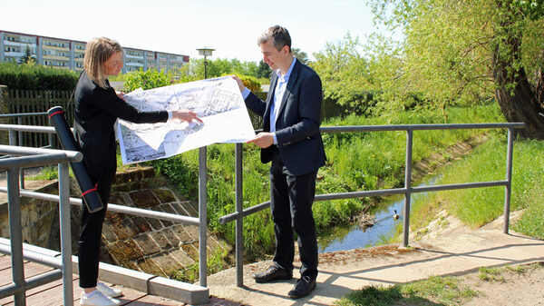 Louisa Schoeneich, Stadplanerin Stadtplanungsamt, und Baubürgermeister Stephan Kühn mit einem Plan auf einer kleinen Brücke