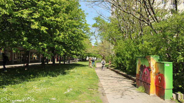 Fußweg mit Grünstreifen und bunt bemalten Leitungskästen