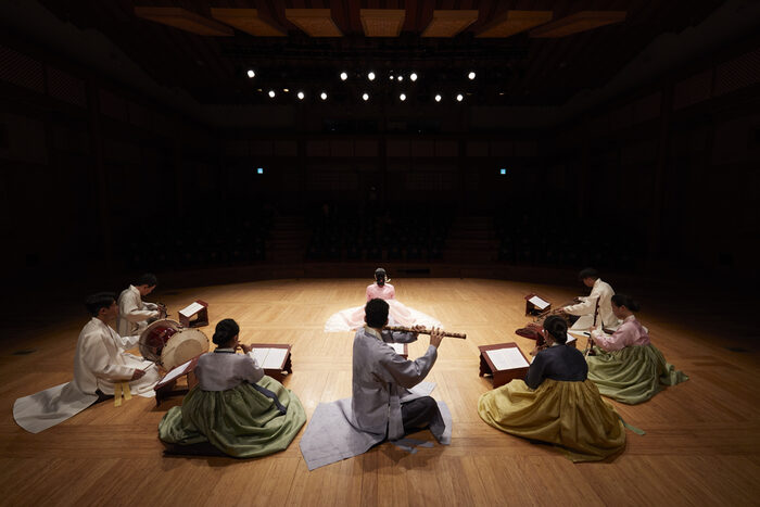 Koreanische Musiker mit Instrumenten auf einer Bühne mit einem dunklen Hinterhrund