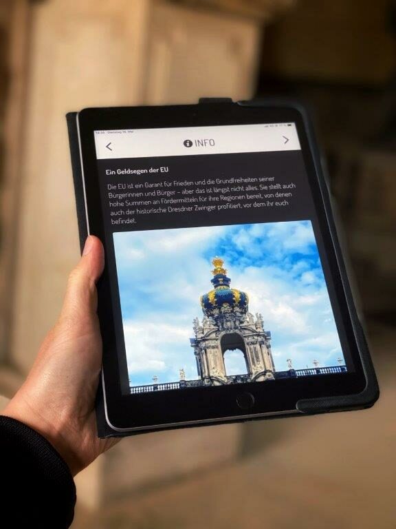 Foto des Zwingers mit Begleittext auf einem Tablet, das von einer Hand gehalten wird