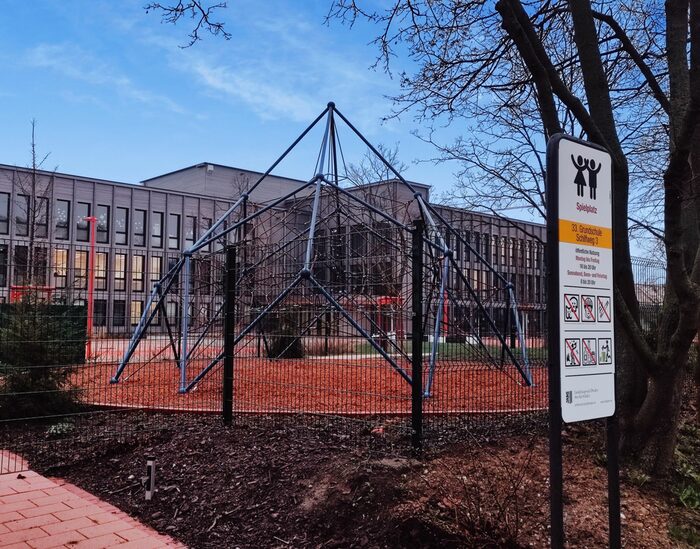 Kletterspinne mit Schulgebäude im Hintergrund