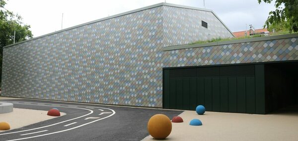 Die geschuppte bunte Fassade mit Gründach von Außen