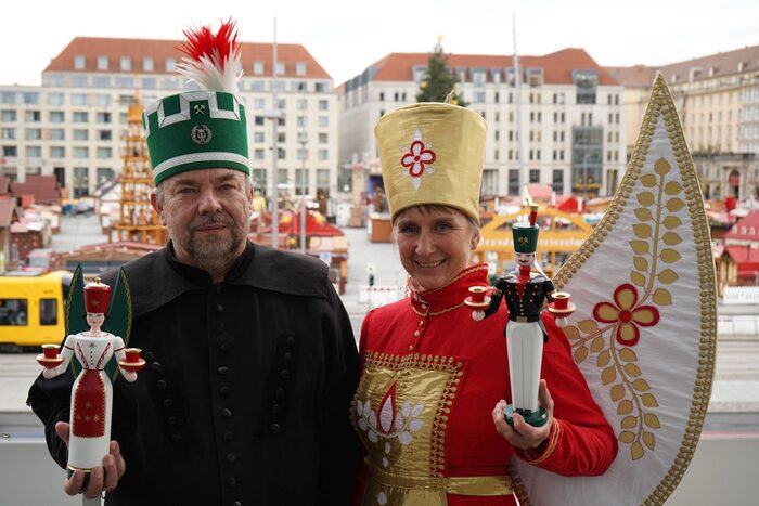 Lebendige Figuren Engel und Bergmann, im Hintergrund ist der Striezelmarkt im Aufbau