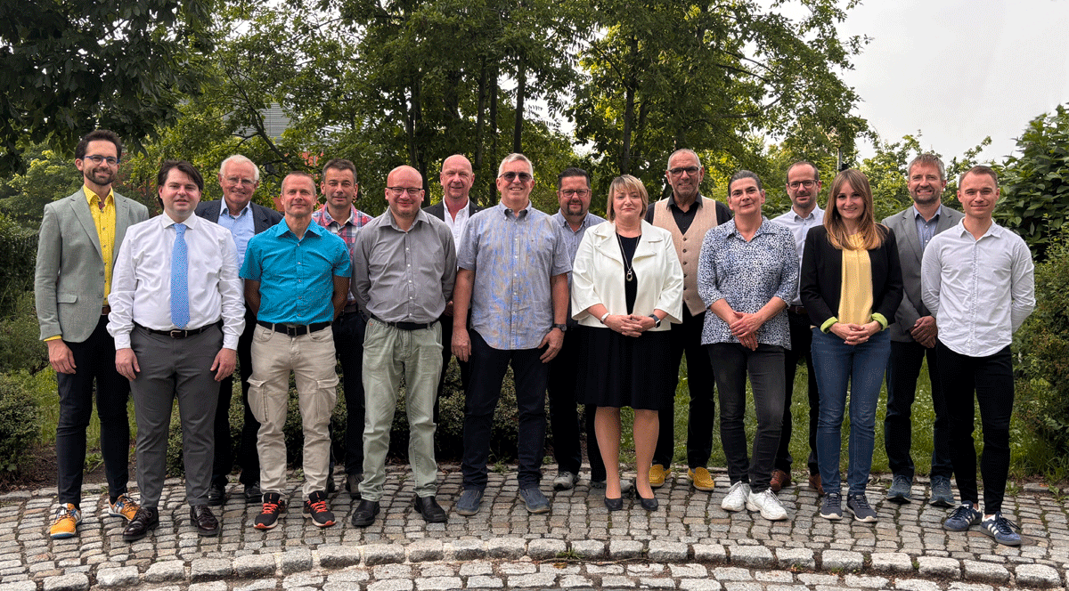 Die Ortschaftsräte stehen in zwei Reihen hintereinander auf einem gepflasterten Fußweg.