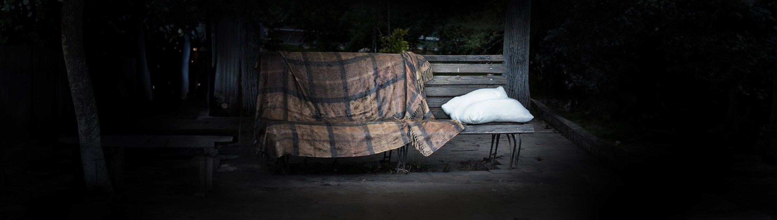 Kissen und Decke auf einer Bank im Dunkeln