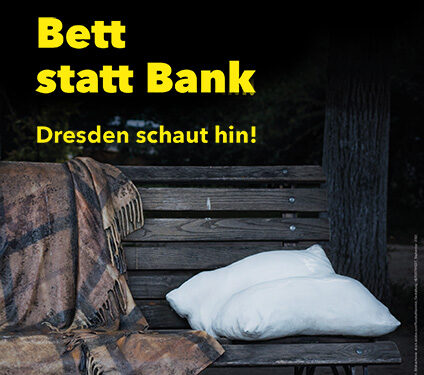 Kissen und Decke auf einer Band mit Schriftzug "Bett statt Bank - Dresden schaut hin"