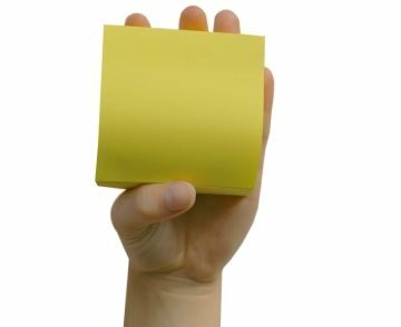 Zu sehen ist eine Hand, die einen gelben Zettelblock hochhält.
