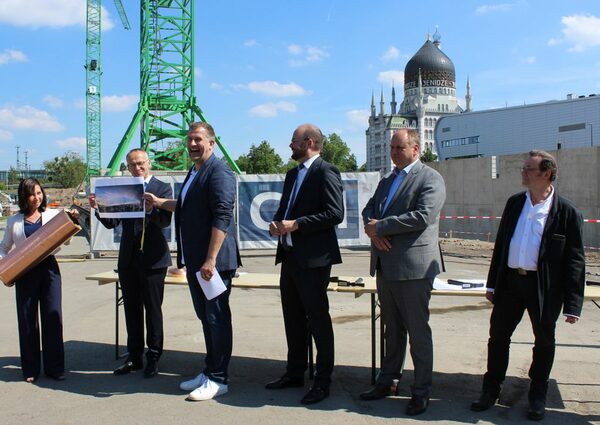 Sport- und Finanzbürgermeister Dr. Peter Lames packt einen Münzsatz und die Visualisierung des Stadions mit hinein
