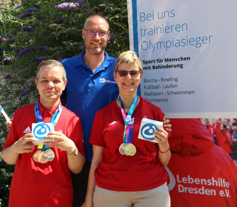 Ingo Noderer, Sportkoordinator der Lebenshilfe Dresden (blaues Shirt) mit den Dresdner Boccia-Sportlern, Frank und Dörte zeigen stolz ihre Medaillen der Special Olympics World Games