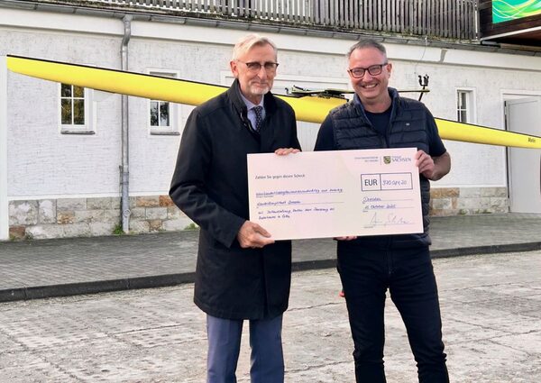 Innenminister Armin Schuster (li) übergibt Sportbürgermeister Jan Donhauser (re) den Fördermittelbescheid, in Form eines Schecks, für die Sanierung des Bootshauses Cotta