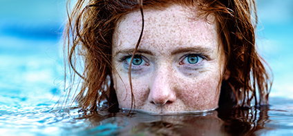 Rothaarige Frau mit großen grünen Augen im Wasser