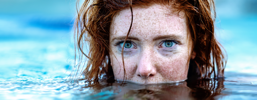 Rothaarige Frau mit großen grünen Augen im Wasser