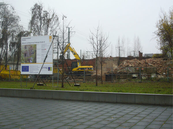 Gebäudeabbruch, der Bagger beginnt mit dem Abbruch der Ruine, im Vordergrund des Bildes steht das Bauschild