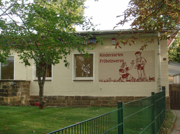 Fassadengestaltung mit Erneuerung der Wandmalerei - Schriftzug "Kindergarten Fröbelzwerge" und ein Mädchen mit einem Jungen beim Blumen pflücken