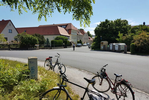 Das Bild zeigt einen Blick in den Dorfkern von Altdobritz von einer Grünfläche aus. Im Vordergrund befinden sich Fahrräder.