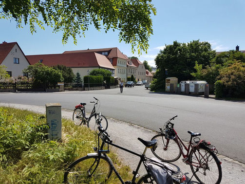 Das Bild zeigt einen Blick in den Dorfkern von Altdobritz von einer Grünfläche aus, Fahrräder im Vordergrund.