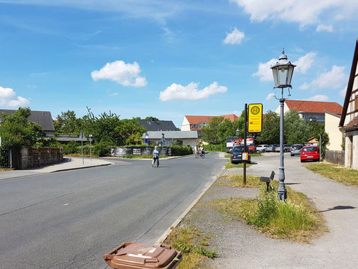 Das Bild zeigt den jetzigen Anblick des Dorfkerns von Altdobritz mit überbreitem Verkehrsraum und Bushaltestelle der Linie 86.