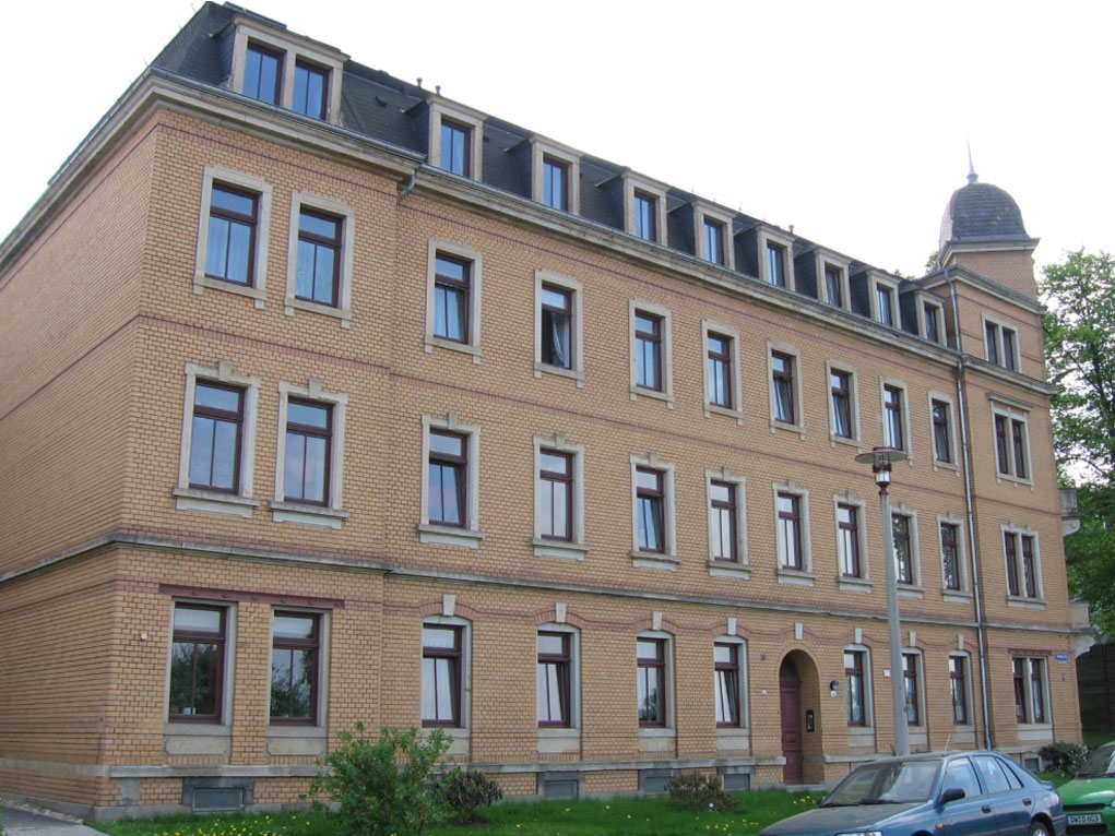 Auf dem Foto ist ein saniertes Wohnhaus auf der Lübecker Str. zu sehen. Es ist ein schlichtes Gründerzeitgebäude mit einer orangefarbenen Klinkerfassade.